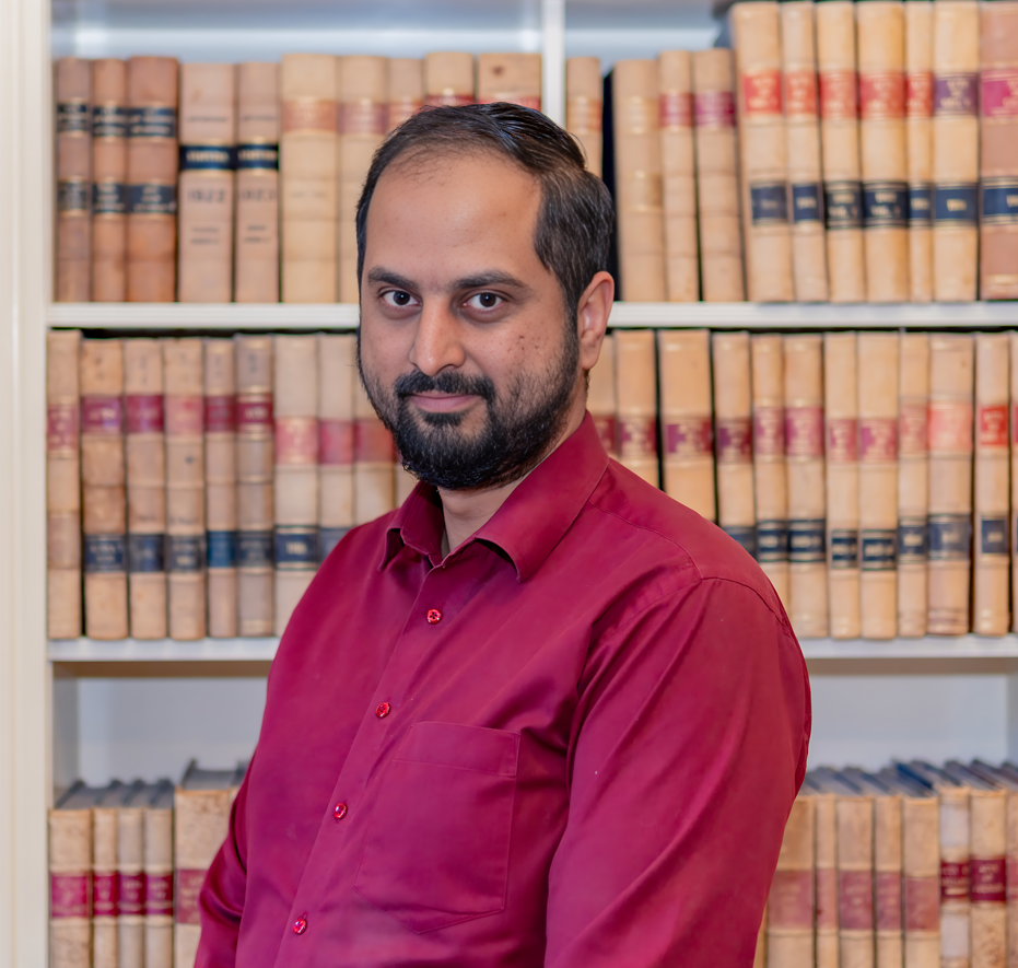Man in red shirt, books behind him