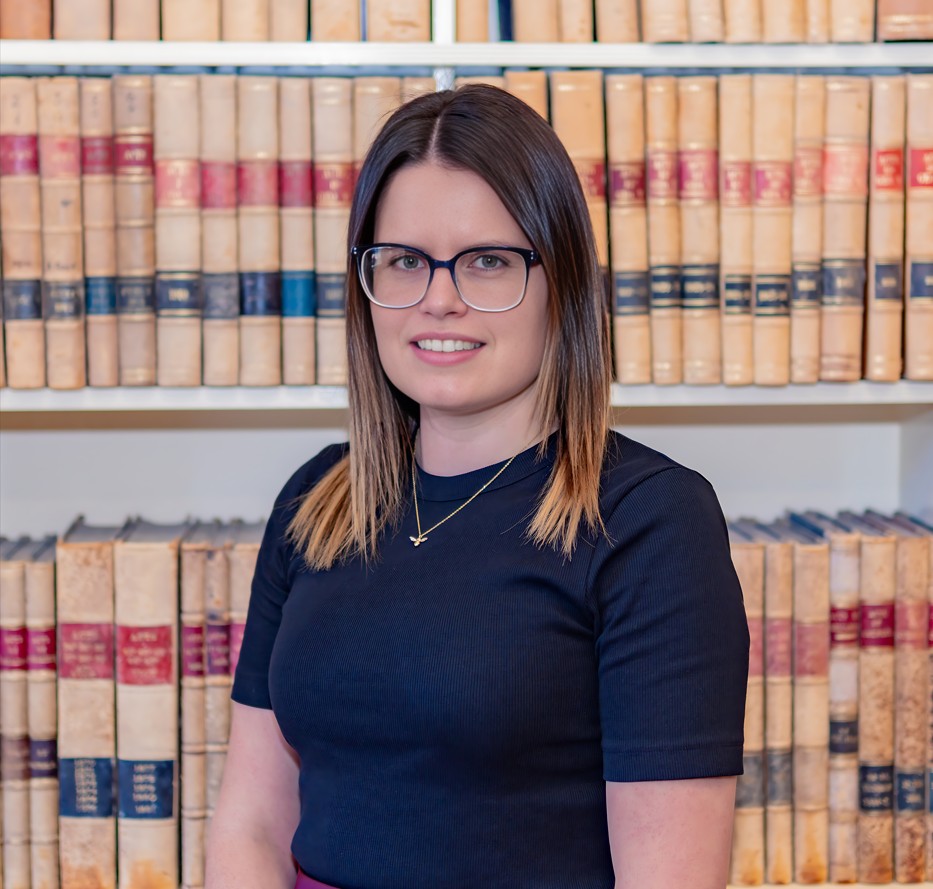 Young woman with glasses, books behind