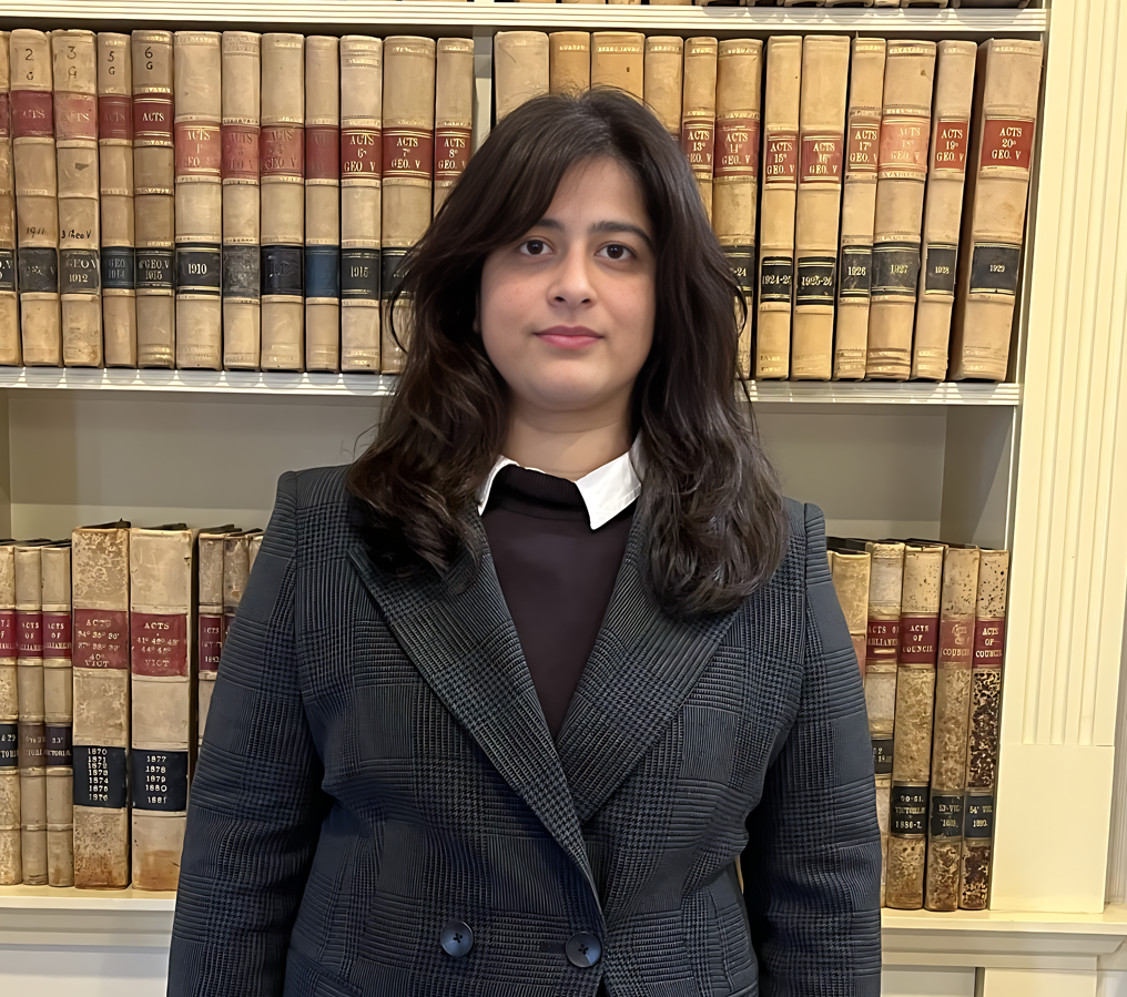 Woman in plaid suit, books behind